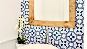 A bathroom with a large blue sink, a wooden-framed mirror, and a patterned tile backsplash. - Tyrrhenian Sea View Apartment (Campania)