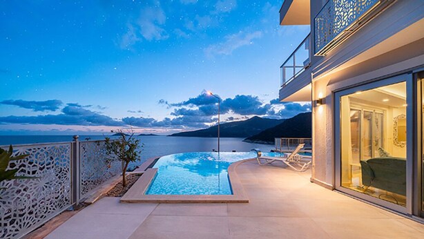 Una piscina con vista sul mare e sulle montagne al crepuscolo.