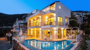 Una casa a due piani con piscina, balconi e vista sul paesaggio circostante.