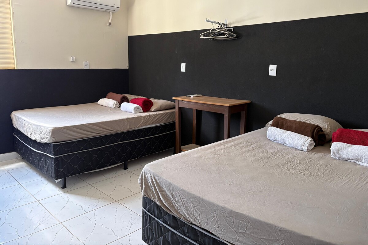 Habitación de hotel con dos camas, una mesita y un equipo de aire acondicionado.