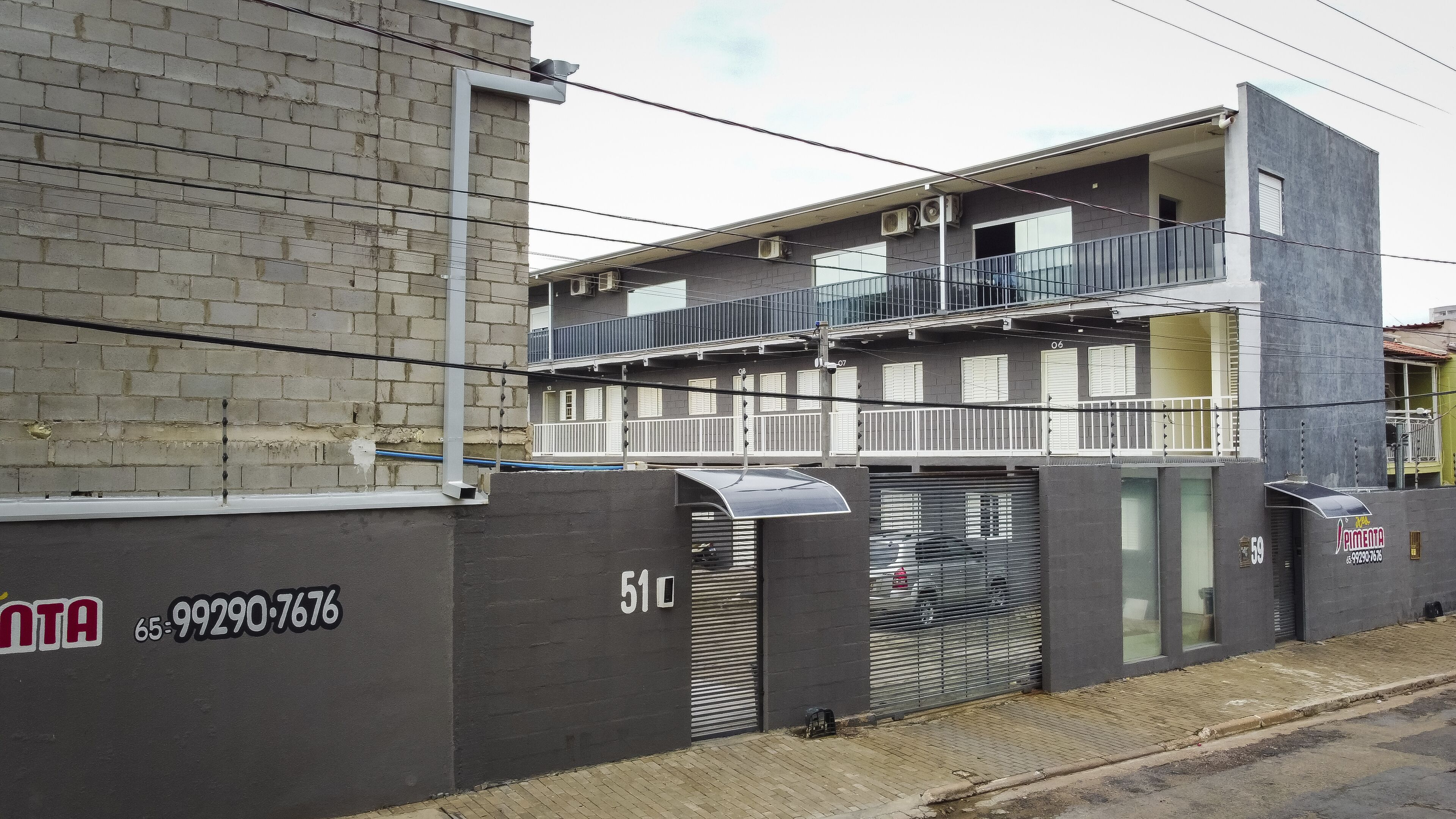 A multi-story building with a grey facade, balconies, and a garage door.