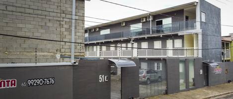A multi-story building with a grey facade, balconies, and a garage door.