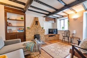 Una sala de estar acogedora con chimenea, televisor y estantería.