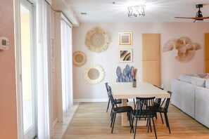 A modern dining area with a wooden table, black chairs, and a ceiling fan. - Sojourn Sanctuary Seaside Escape (Virginia Beach)