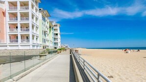 A beachfront promenade with multi-story buildings, a sandy beach, and a clear blue sky. - Sojourn Sanctuary Seaside Escape (Virginia Beach)