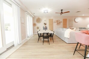 Ein geräumiges Zimmer mit Esstisch, Stühlen, einer Couch und einem Deckenventilator.