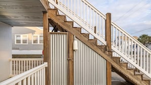 Un escalier en bois, doté de rampes blanches, mène à une entrée abritée.