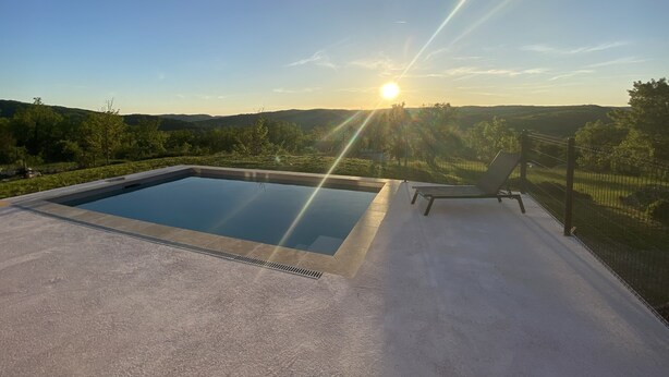 Une piscine avec vue sur le coucher de soleil et les collines.
