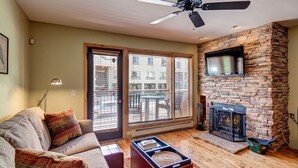 A living room with a sofa, a coffee table, a fireplace, and a ceiling fan. - Beautiful Condo Central to Main Street and Peak 9! (Breckenridge)