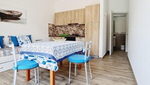 Un comedor con una mesa dispuesta para cuatro personas, armarios de madera y un ventilador de techo.
