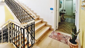 A staircase with a geometric railing leading to a room with a patterned rug and a potted plant. - Appartamento lu Sule (Porto cesareo)