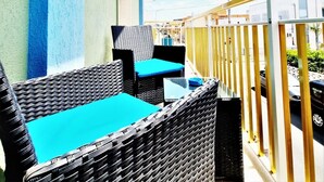 A balcony with wicker furniture and a view of the street. - Appartamento lu Sule (Porto cesareo)