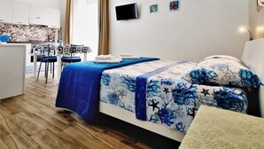 A modern hotel room with a bed, a desk, and a kitchenette. - Appartamento lu Sule (Porto cesareo)
