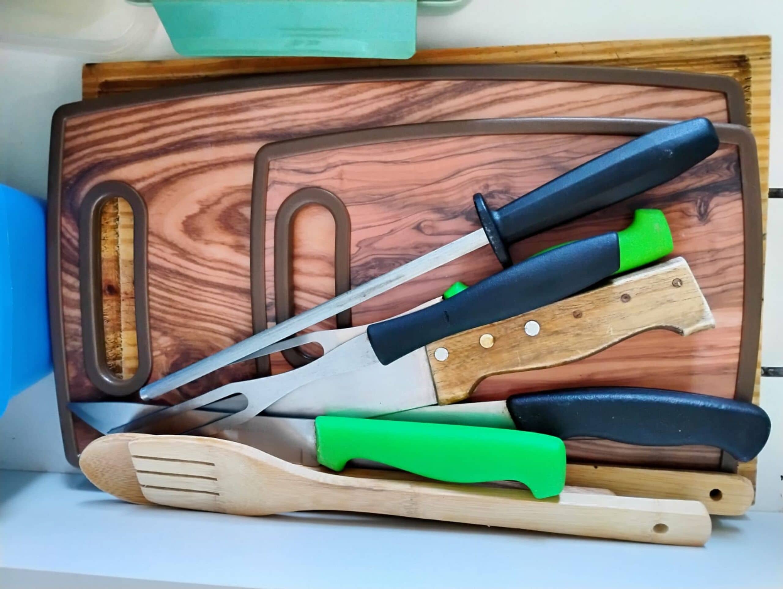 Ein Holzschneidebrett mit verschiedenen Küchenutensilien, darunter ein Messer, ein Löffel und eine Zange.