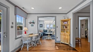 A spacious room with a dining area, a sofa, and a bookshelf. - Whispering Oaks 3 Bedroom Home by RedAwning (Harkers Island)