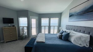 Un dormitorio con una cama grande, un aparador, un televisor y un balcón con vistas.