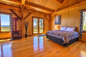 Ein Schlafzimmer einer Holzhütte mit einem Bett, einem Kamin und einem großen Fenster.