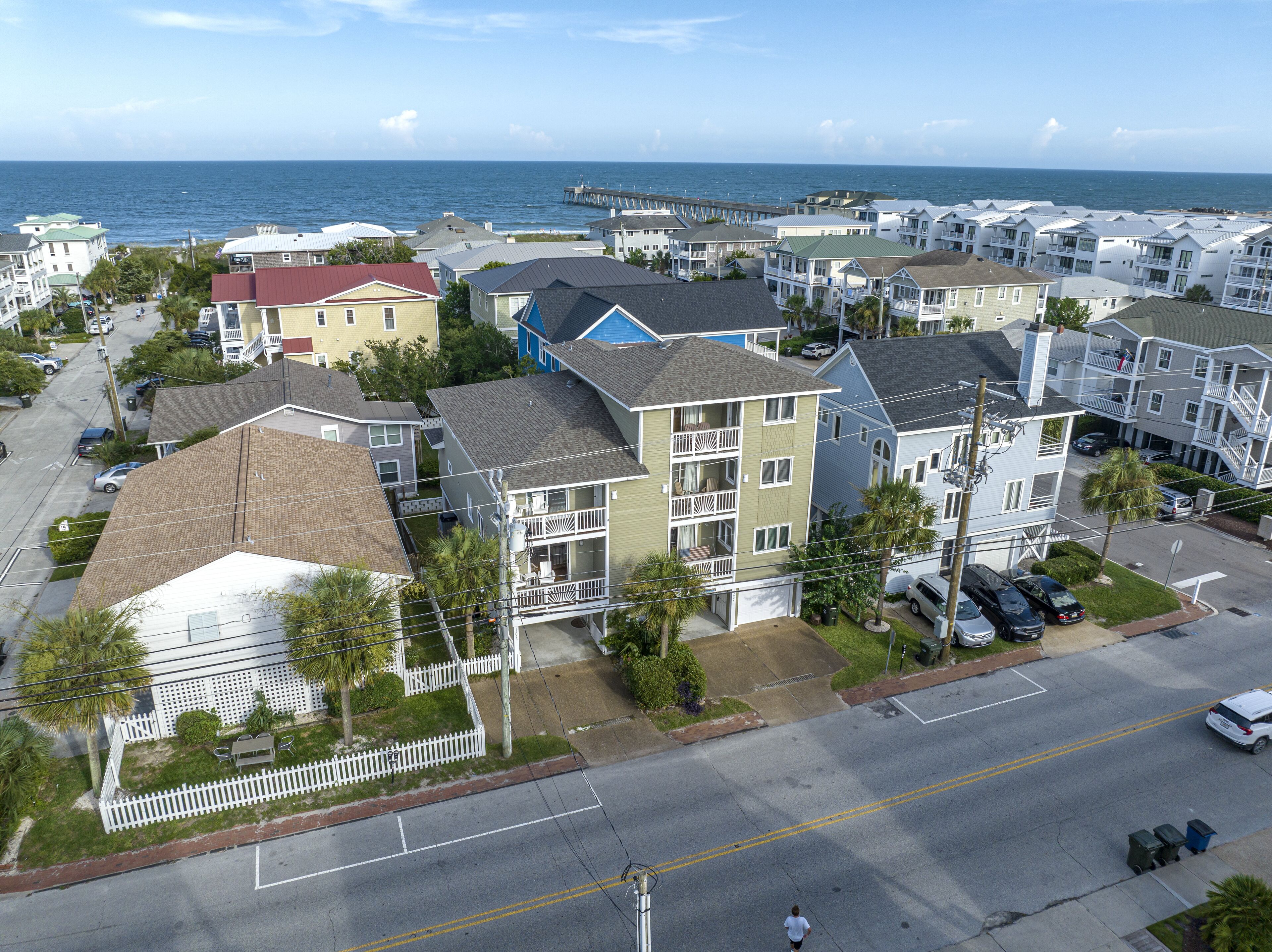A coastal residential area with multi-story buildings, a pier, and a view of the ocean.