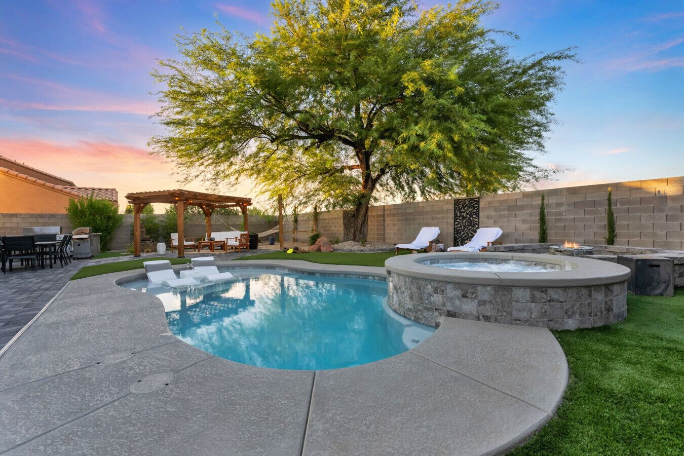 Un jardin avec une piscine, un jacuzzi et un espace salon extérieur.