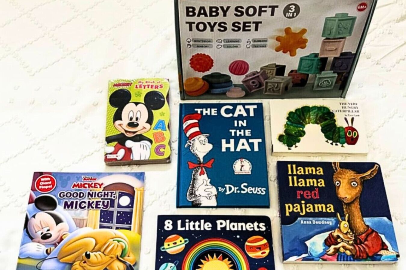 Een verzameling kinderboeken en speelgoed, waaronder 'The Cat in the Hat' van Dr. Seuss, 'Goodnight Mickey', 'Llama Llama Red Pajama' en '8 Little Planets'.