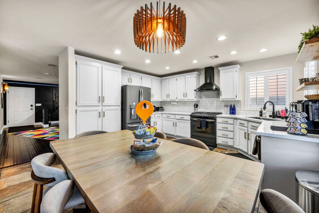Une cuisine moderne avec des meubles blancs, un îlot central et un luminaire suspendu orange original.