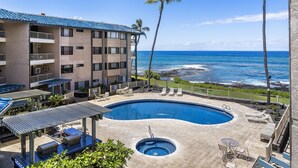 A hotel with a pool, outdoor seating, and a view of the ocean.
