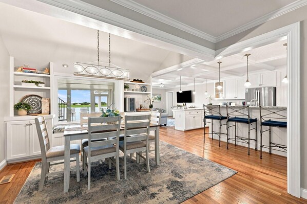 A spacious kitchen with a dining area, wooden flooring, and a view of the outdoors.