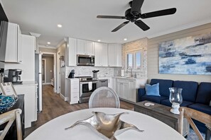 Una cocina moderna con armarios blancos, microondas y una zona de comedor con una mesa redonda y sillas.