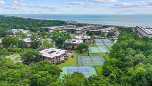 Ein Luftbild eines Wohngebiets mit mehreren Mehrfamilienhäusern, Tennisplätzen und üppiger Bepflanzung.
