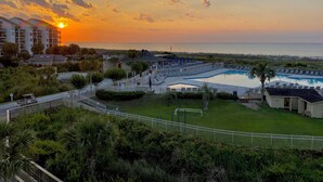 Ein Resort mit Schwimmbad, Blick auf den Strand und Sonnenuntergang.