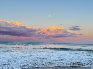 A beach with waves and a sunset sky.