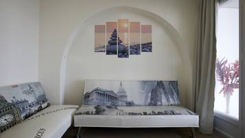 Una stanza con un divano, un quadro che raffigura una veduta cittadina e un'opera d'arte appesa al muro.