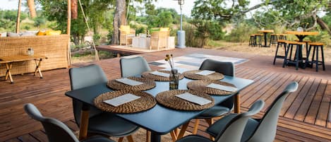 An outdoor dining area with round tables, chairs, and a buffet setup.