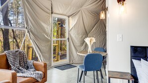 A cozy interior with a large window, a dining area, and a bed.