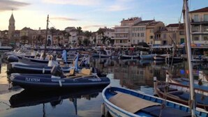 A marina with boats docked, a clock tower in the background, and buildings along the waterfront. - Superbe Appartement Cosy à 300 m de la Plage (Bandol)
