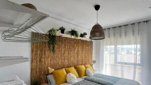 Ein modernes Schlafzimmer mit Bett, Nachttischen, einer Pendelleuchte und Blick ins Freie.