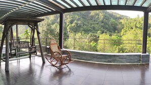 A covered outdoor area with a wooden swing chair and a wooden rocking chair. - Seth Spring B&B (Datong)