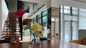 A modern living room with a wooden staircase, a vase with flowers on a table, and large windows. - Seth Spring B&B (Datong)