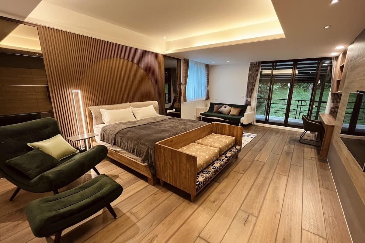 Un dormitorio moderno con una cama grande, un banco de madera y un sillón verde.