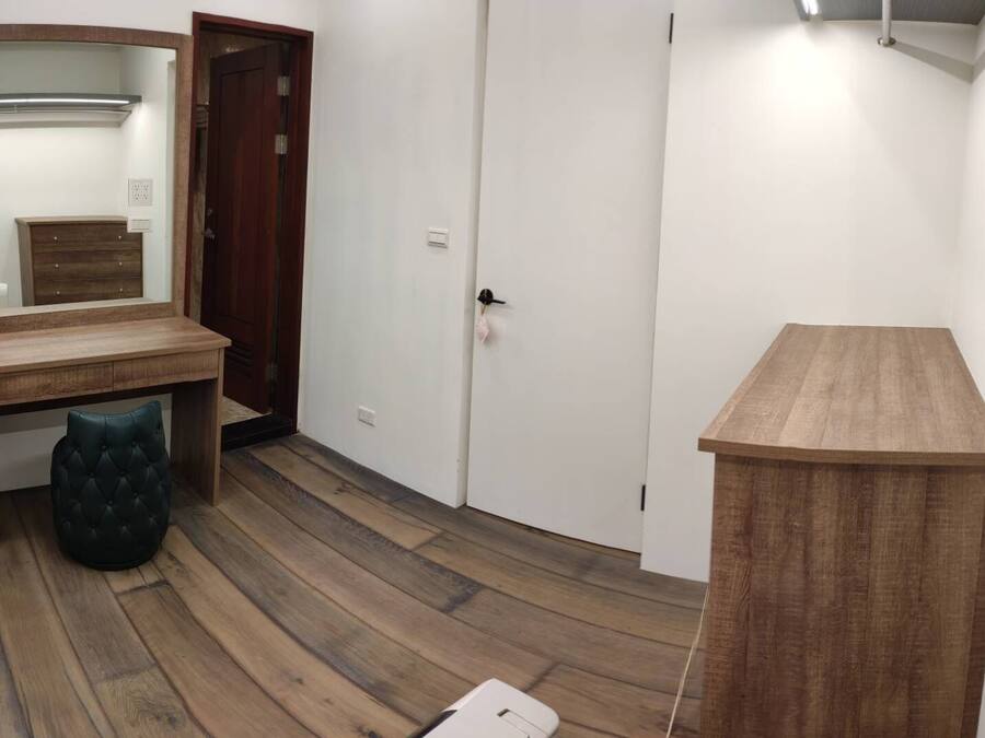 A room with a wooden desk, a chair, a wardrobe, and a bedside table.