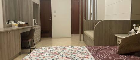 A bedroom with a bed, a desk, a chair, and a wardrobe.