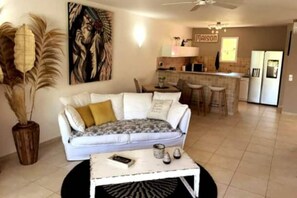 Un salon avec un canapé blanc, une table basse et un tableau accroché au mur.