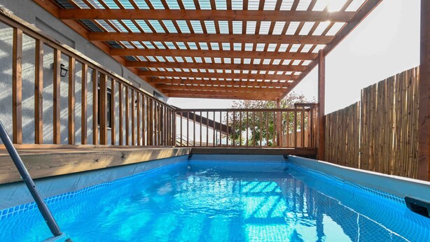 A swimming pool with a wooden pergola overhead, surrounded by a wooden fence. - Yalarent Villa Viviana with private pool (Migdal)