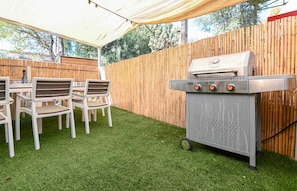 An outdoor patio with a grill, chairs, and a bamboo fence. - Yalarent Villa Viviana with private pool (Migdal)