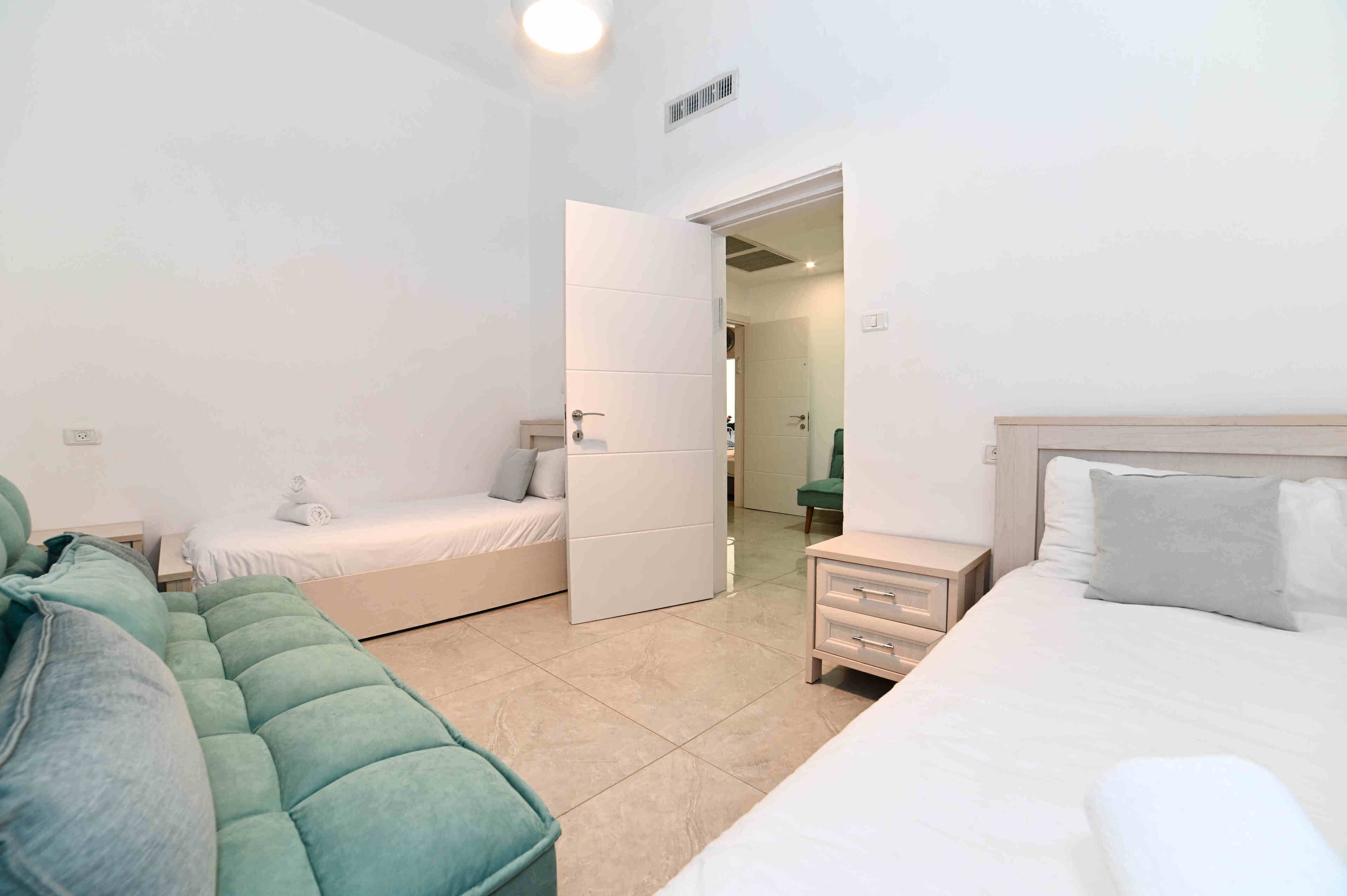 Un dormitorio con cama, sofá, mesita de noche y armario.