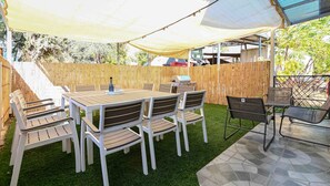An outdoor patio with a table and chairs, a grill, and a wooden fence. - Yalarent Villa Viviana with private pool (Migdal)