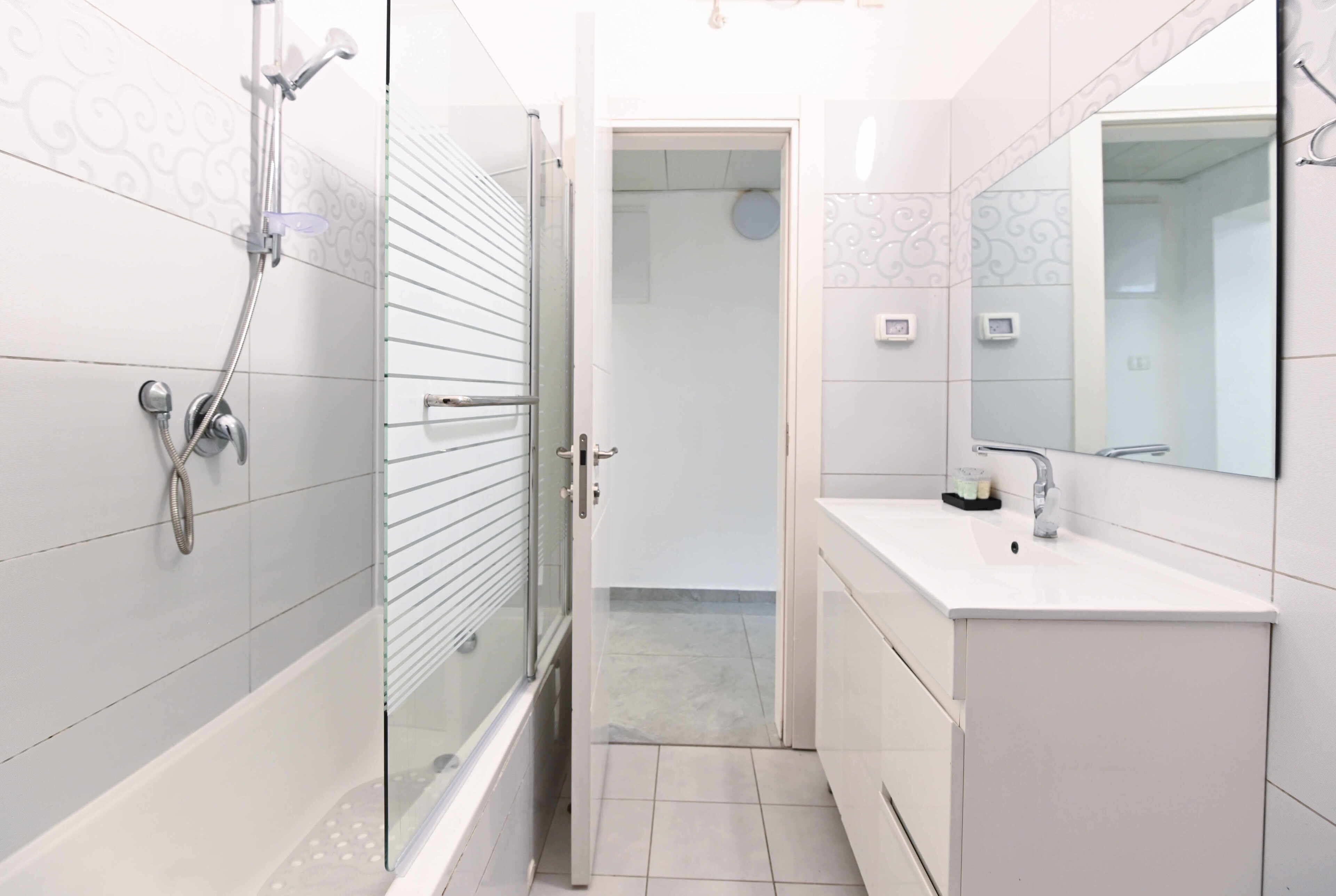 A modern bathroom with a glass shower enclosure, a white sink, and a large mirror.