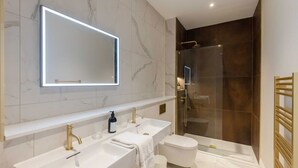 Ein modernes Badezimmer mit großem Spiegel, zwei Waschbecken, Toilette und einer Duschkabine.
