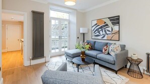 Ein modernes Wohnzimmer mit grauem Sofa, Couchtisch und einem Bild an der Wand.