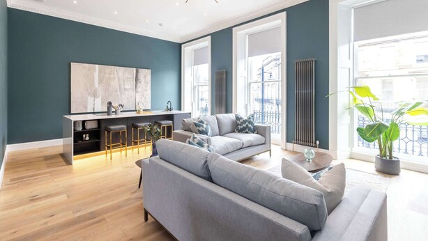 A modern living room with a sofa, a dining area, and a large window with a view.